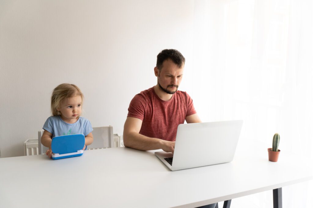 Father and daughter working on laptops at home