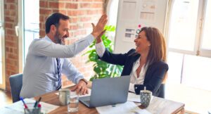 Leadership team high fives at desk with data analysis charts